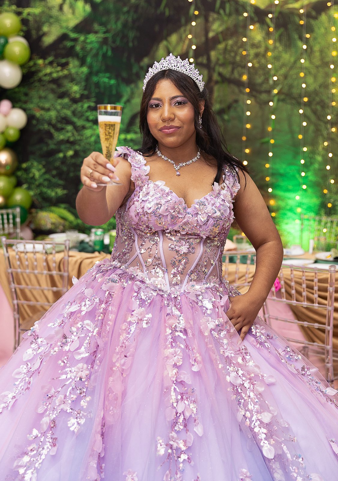 Quinceañera raising a champagne glass in a lavender gown